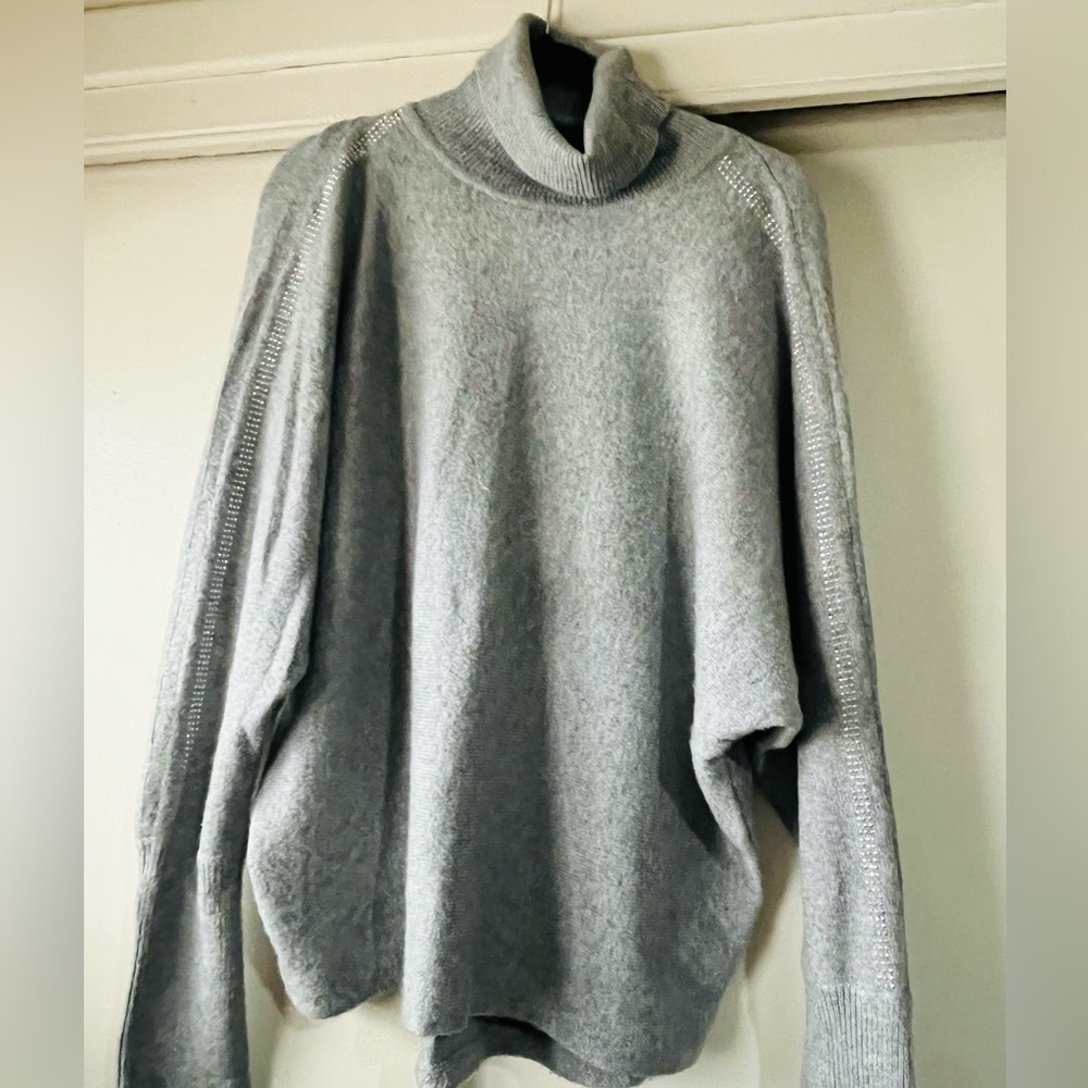 Gray Jennifer Lopez turtleneck sweater with rhinestone detail on sleeve.